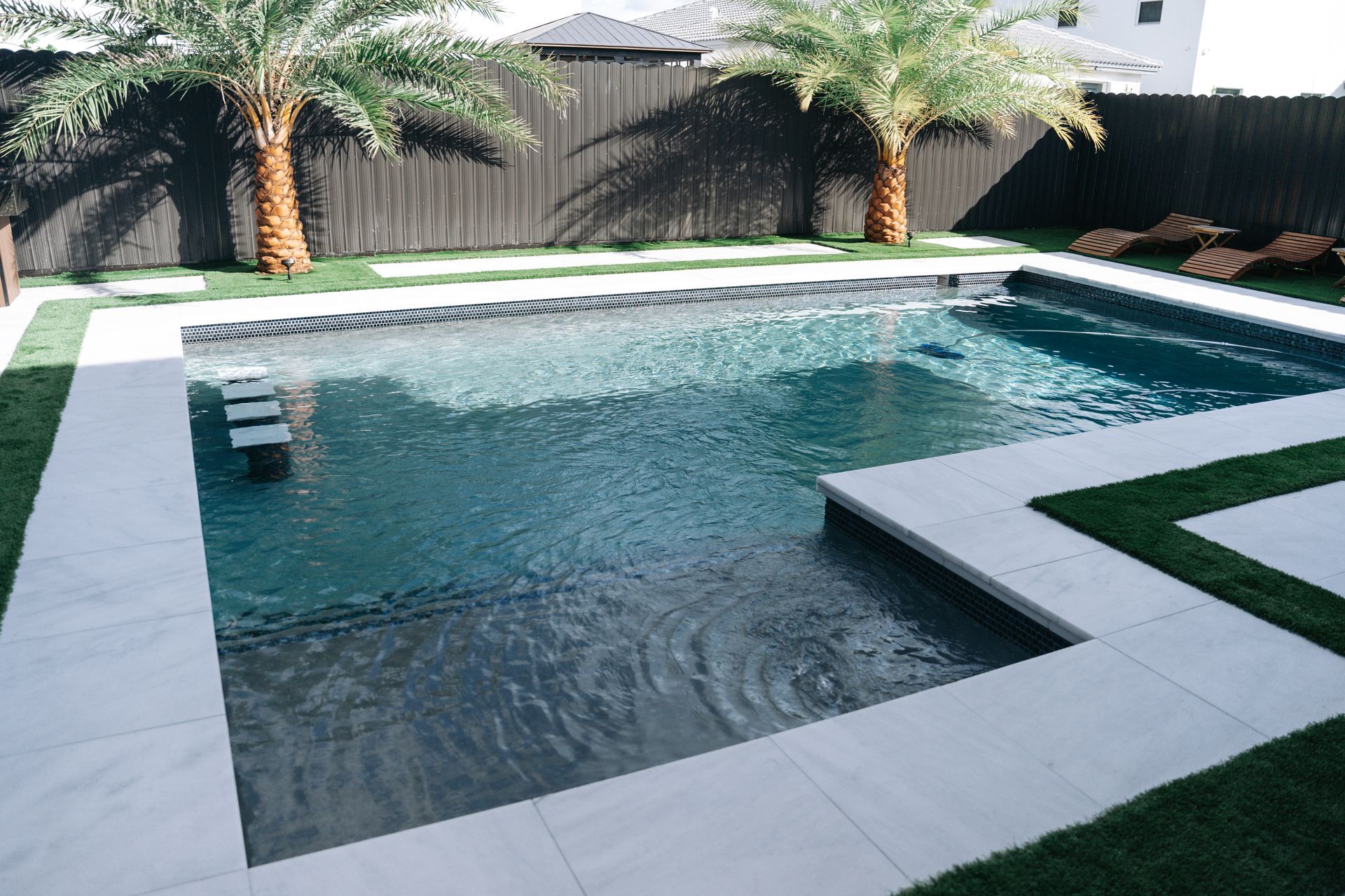 A large swimming pool with palm trees in the backyard