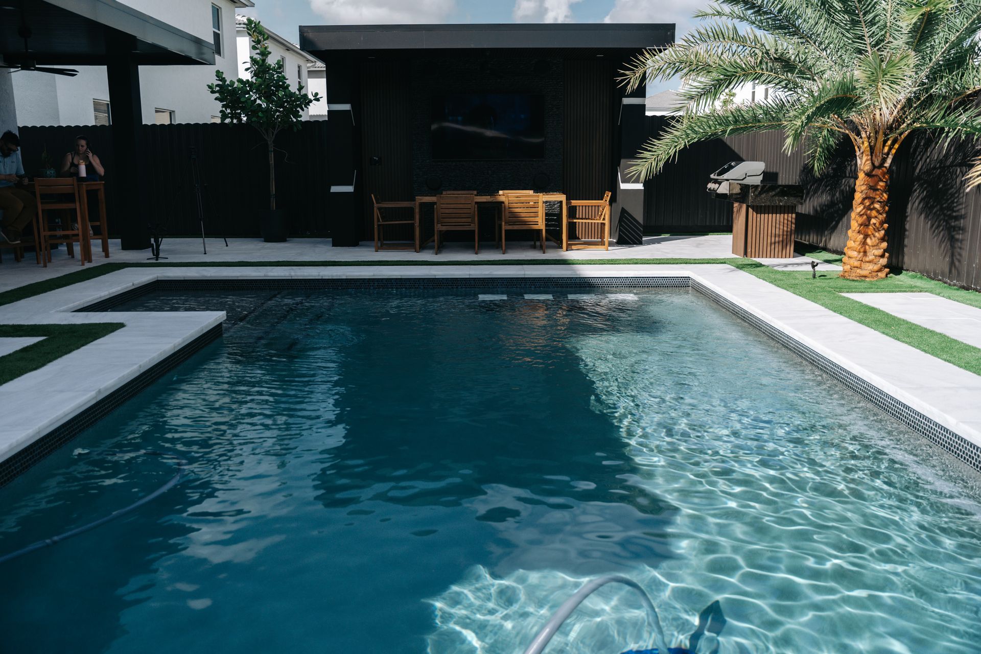 There is a large swimming pool in the backyard of a house.