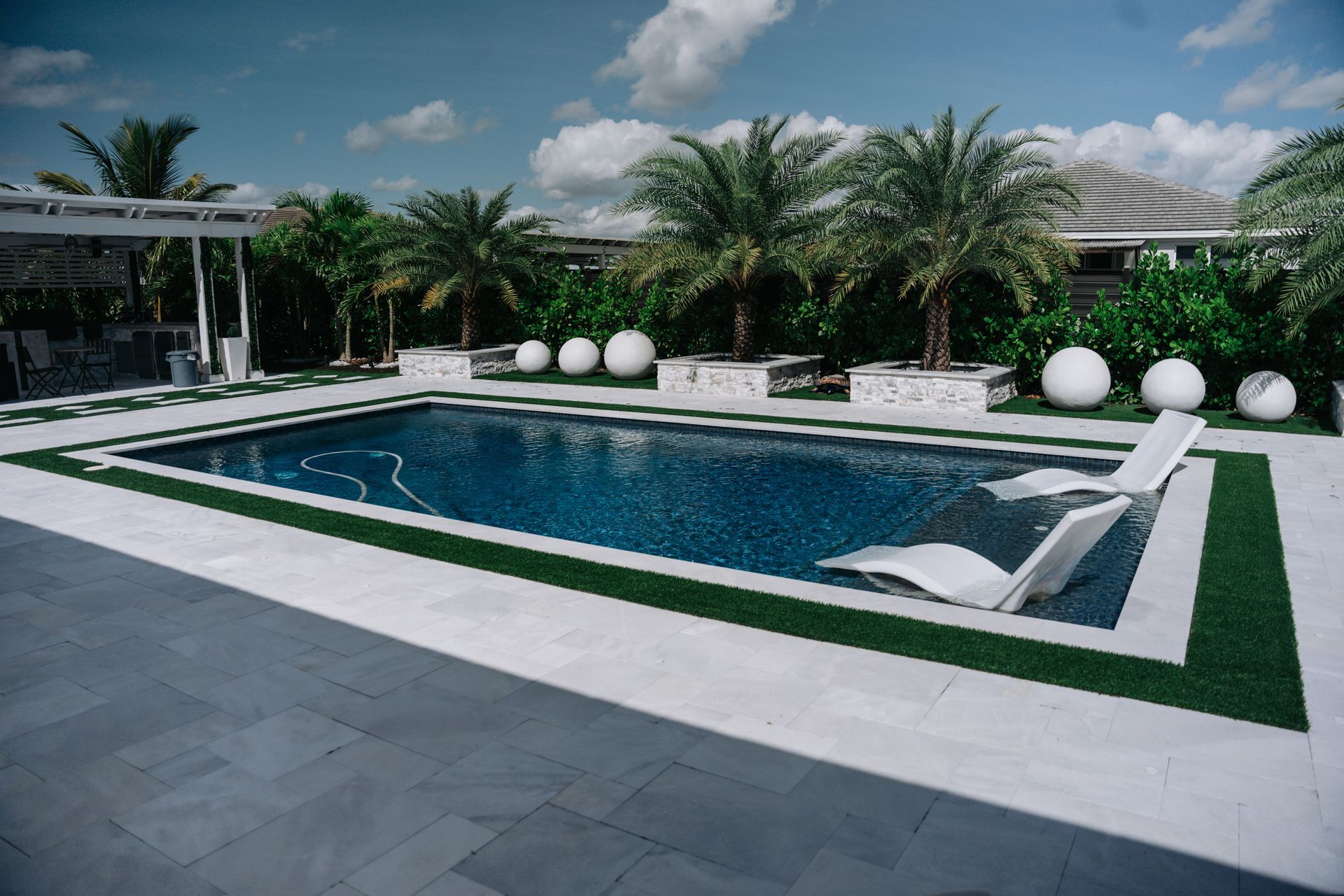 A large swimming pool surrounded by palm trees and lawn chairs.