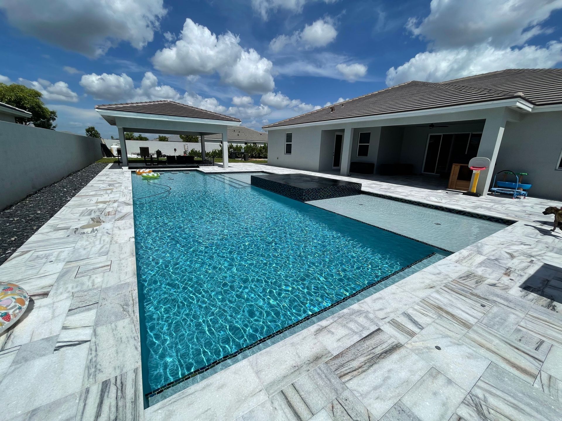 There is a large swimming pool in the backyard of a house.