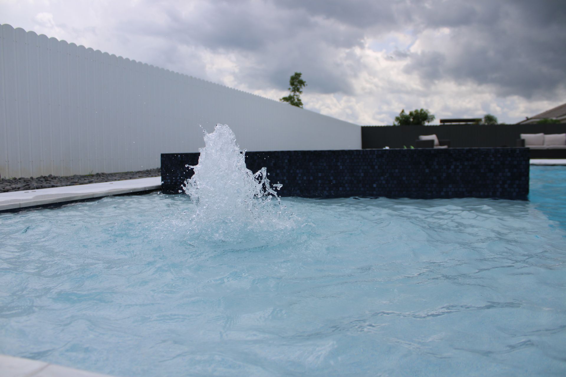 A swimming pool with a fountain in the middle of it.