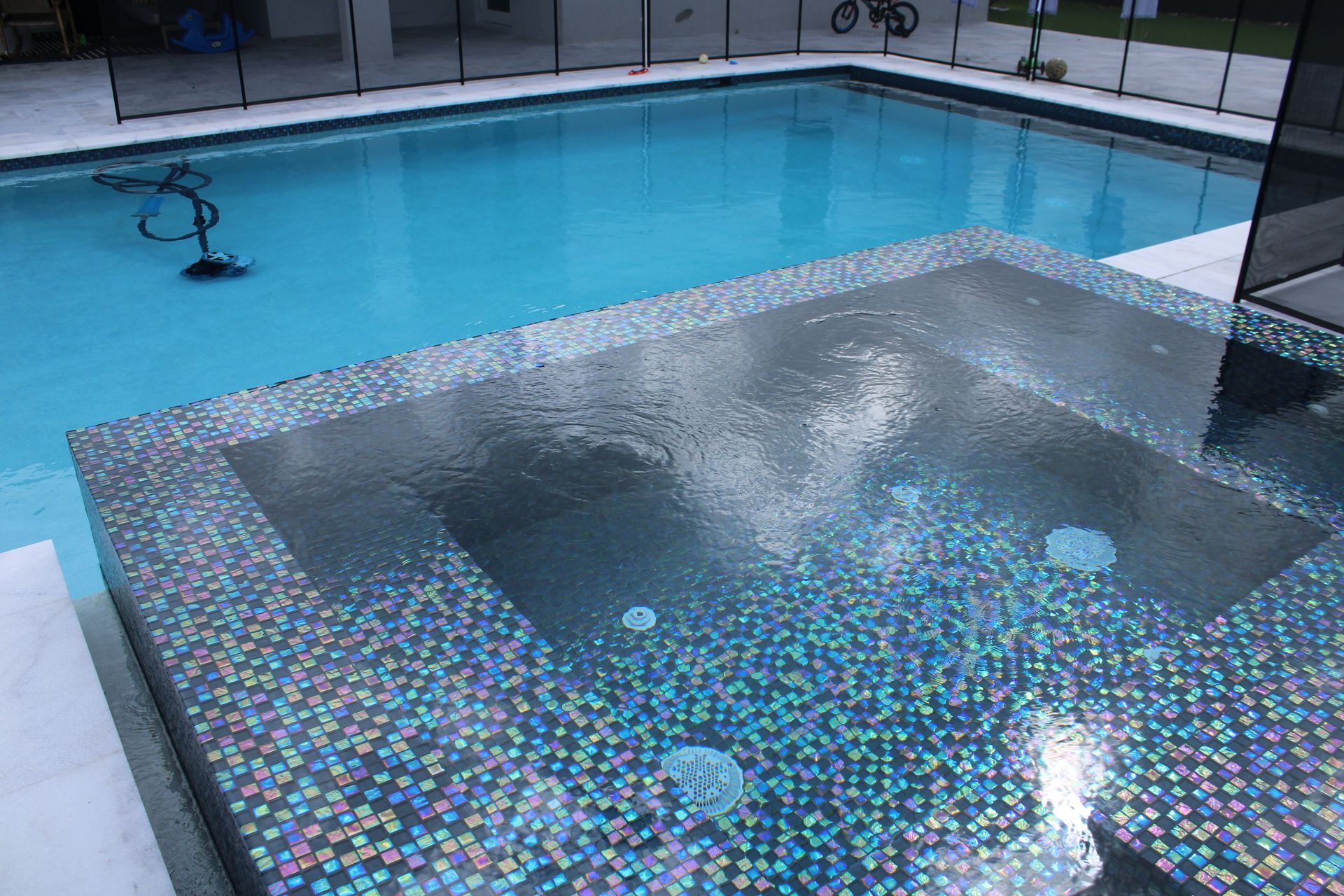 A large swimming pool with a hot tub in the middle of it.