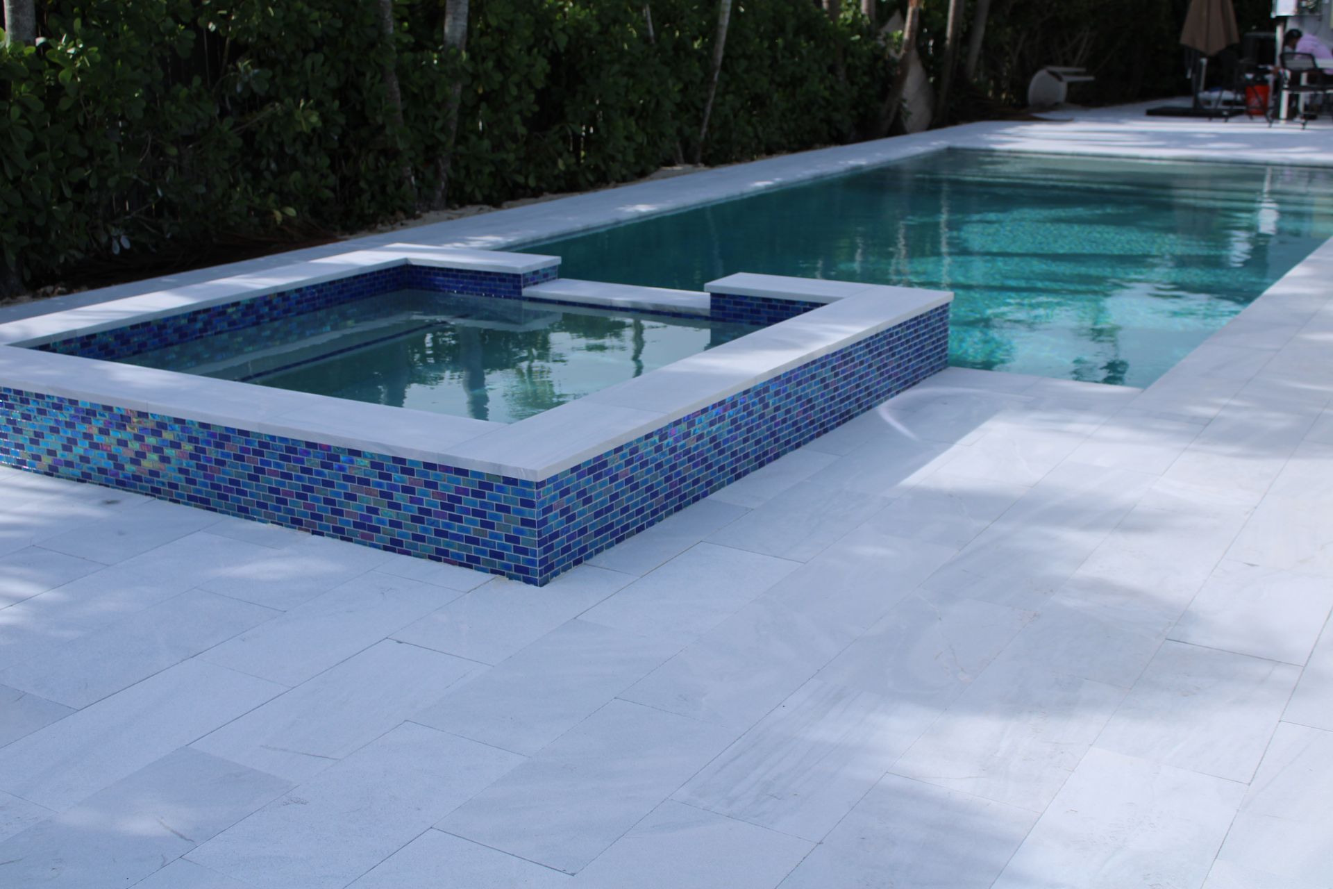 A large swimming pool with a hot tub in the middle of it.