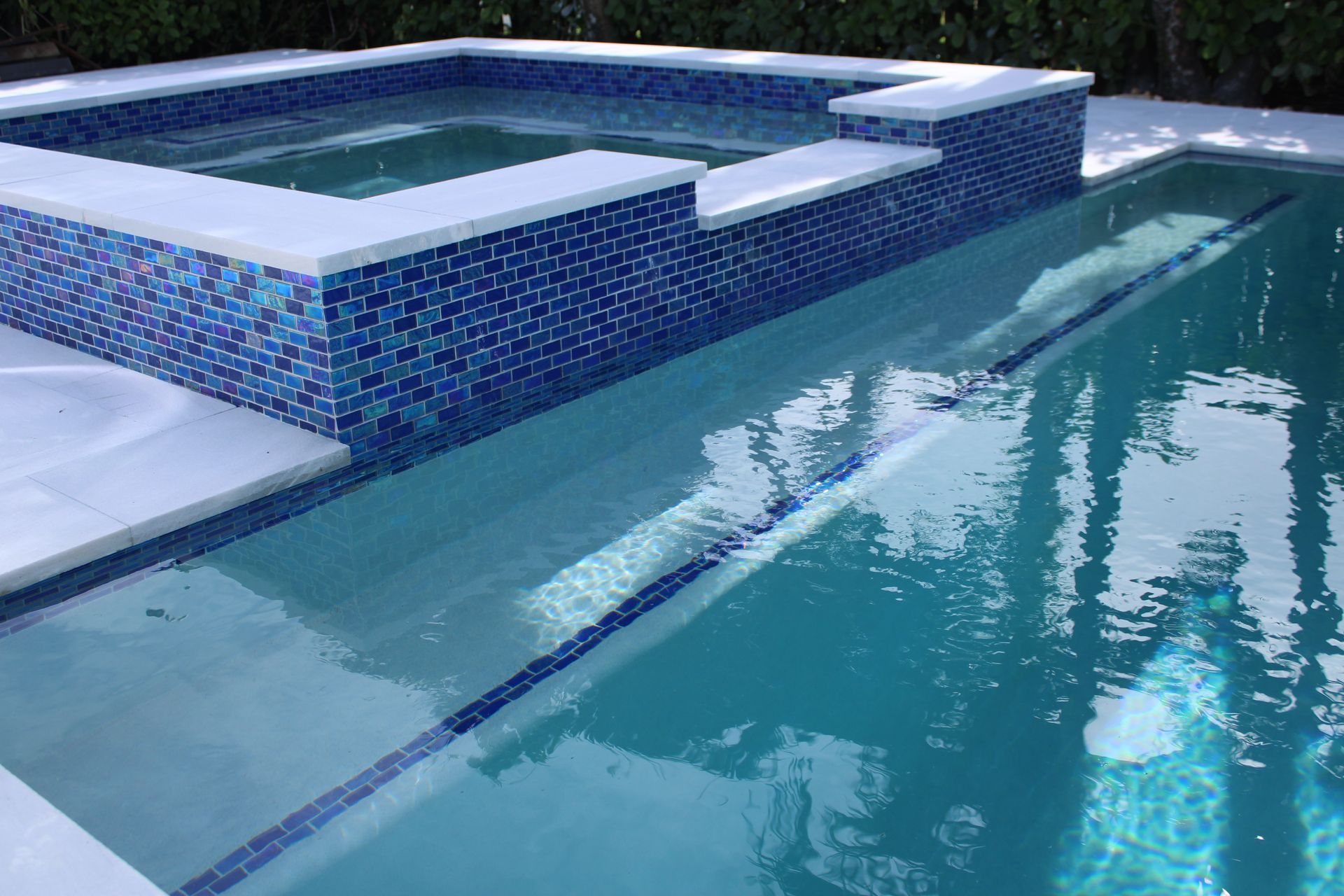 A large swimming pool with a hot tub in the middle of it.
