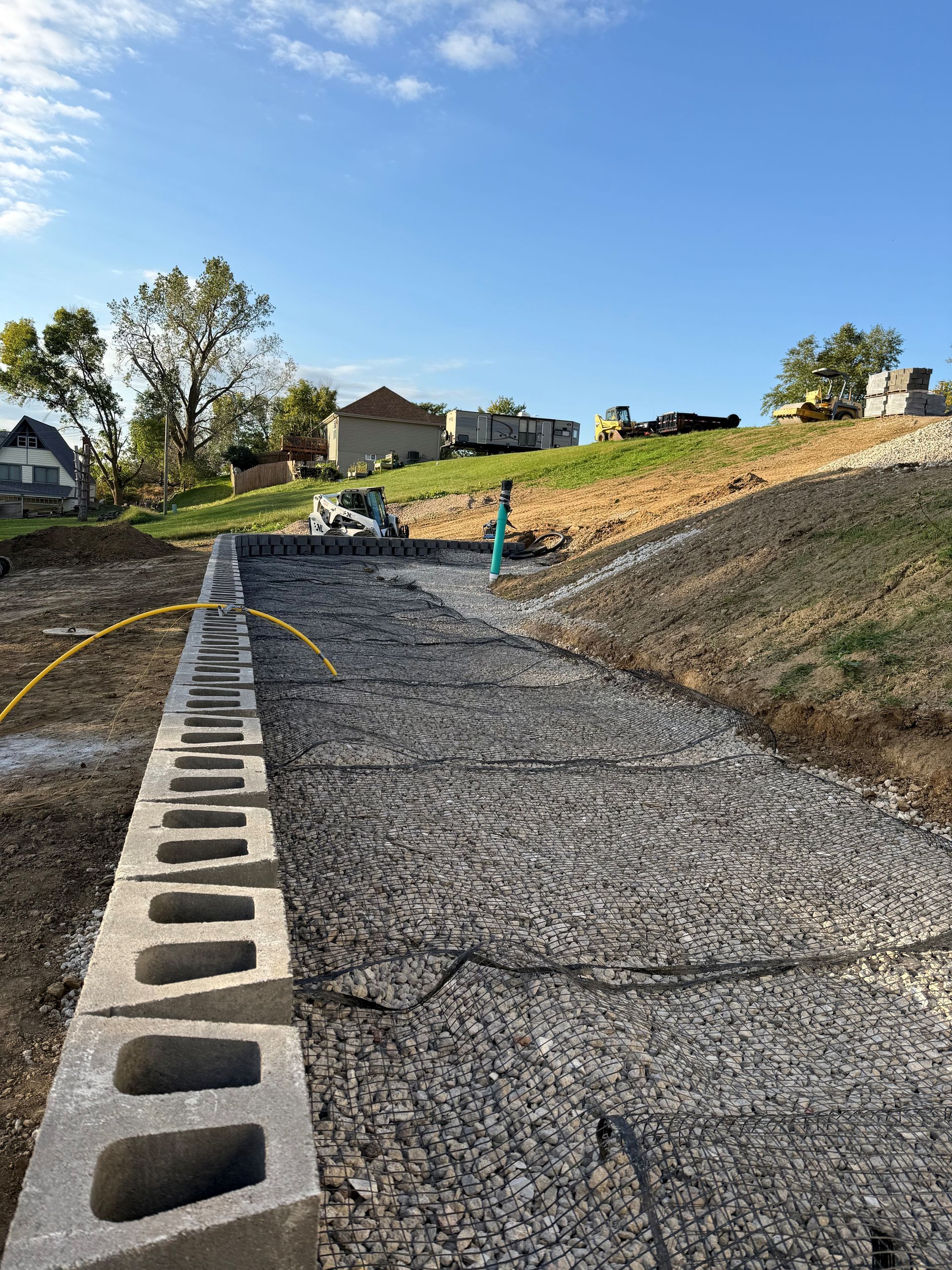 Construction site with cinder block wall, gravel path, and stacked blocks.