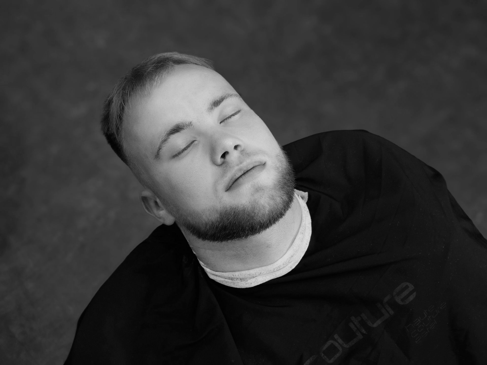 Man with closed eyes, head tilted back, wearing black shirt.