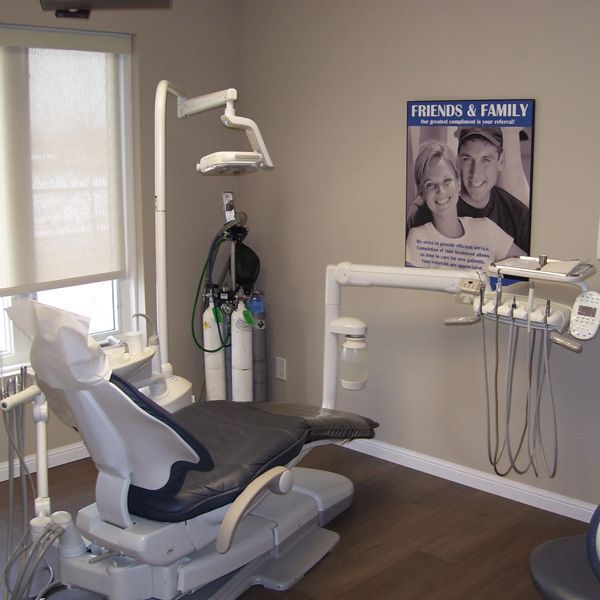 Dental exam room with chair, overhead light, and wall-mounted equipment.