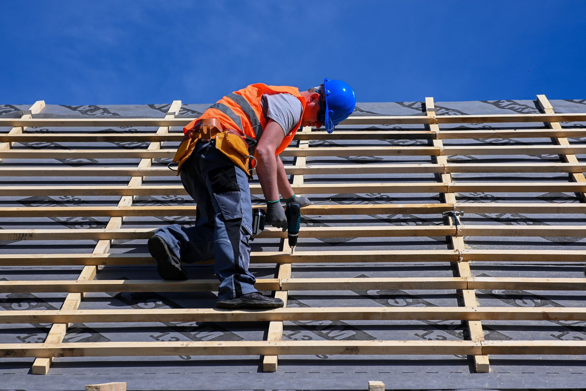 A man is working on a roof with a drill.