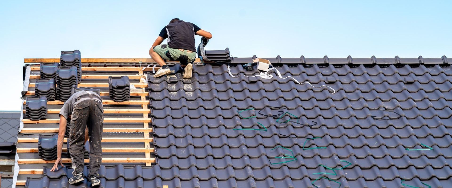 Two men are working on the roof of a house.