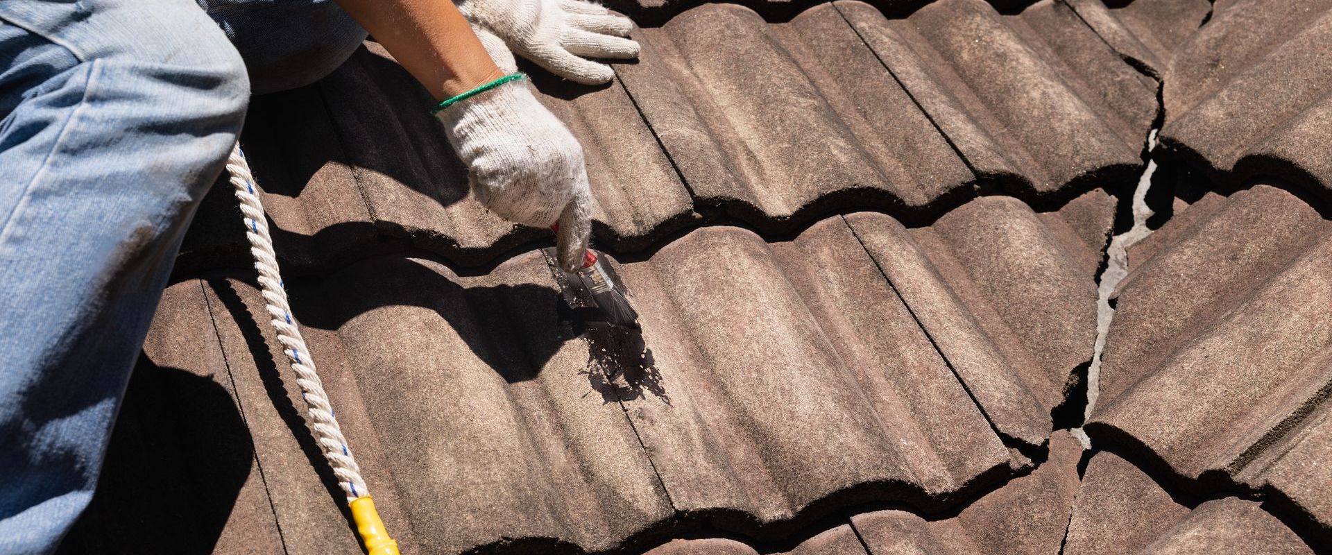 A man is working on a roof with a hammer.