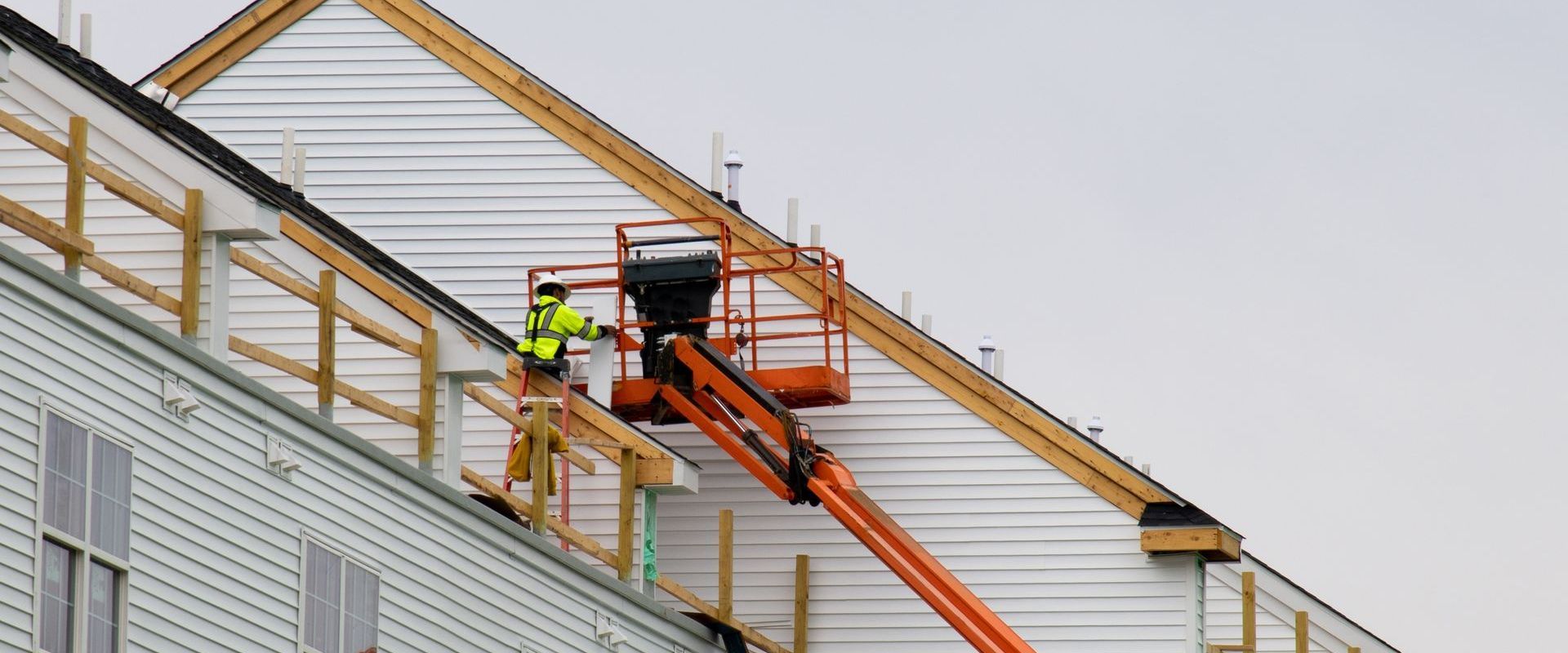A man is working on the roof of a building with a crane.