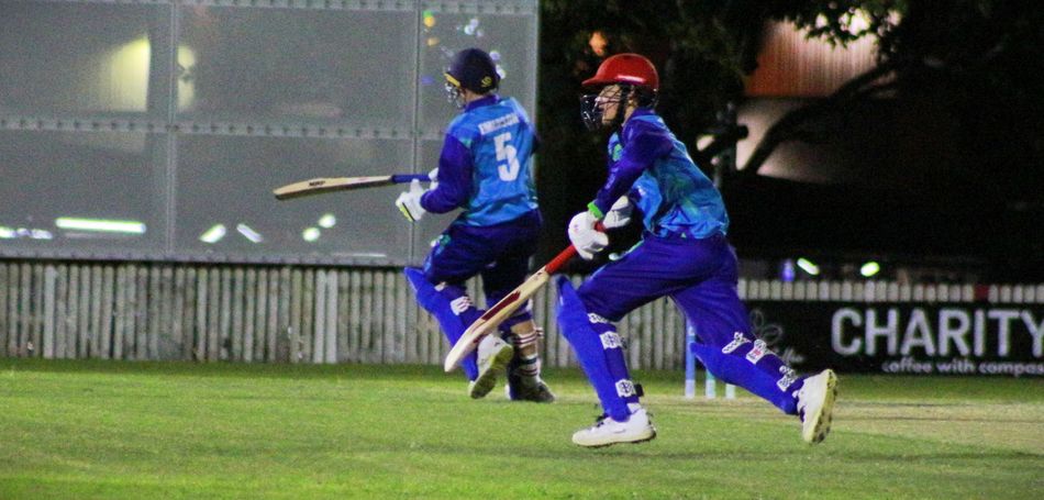 A cricket player with the number 25 on his back is standing on the field.