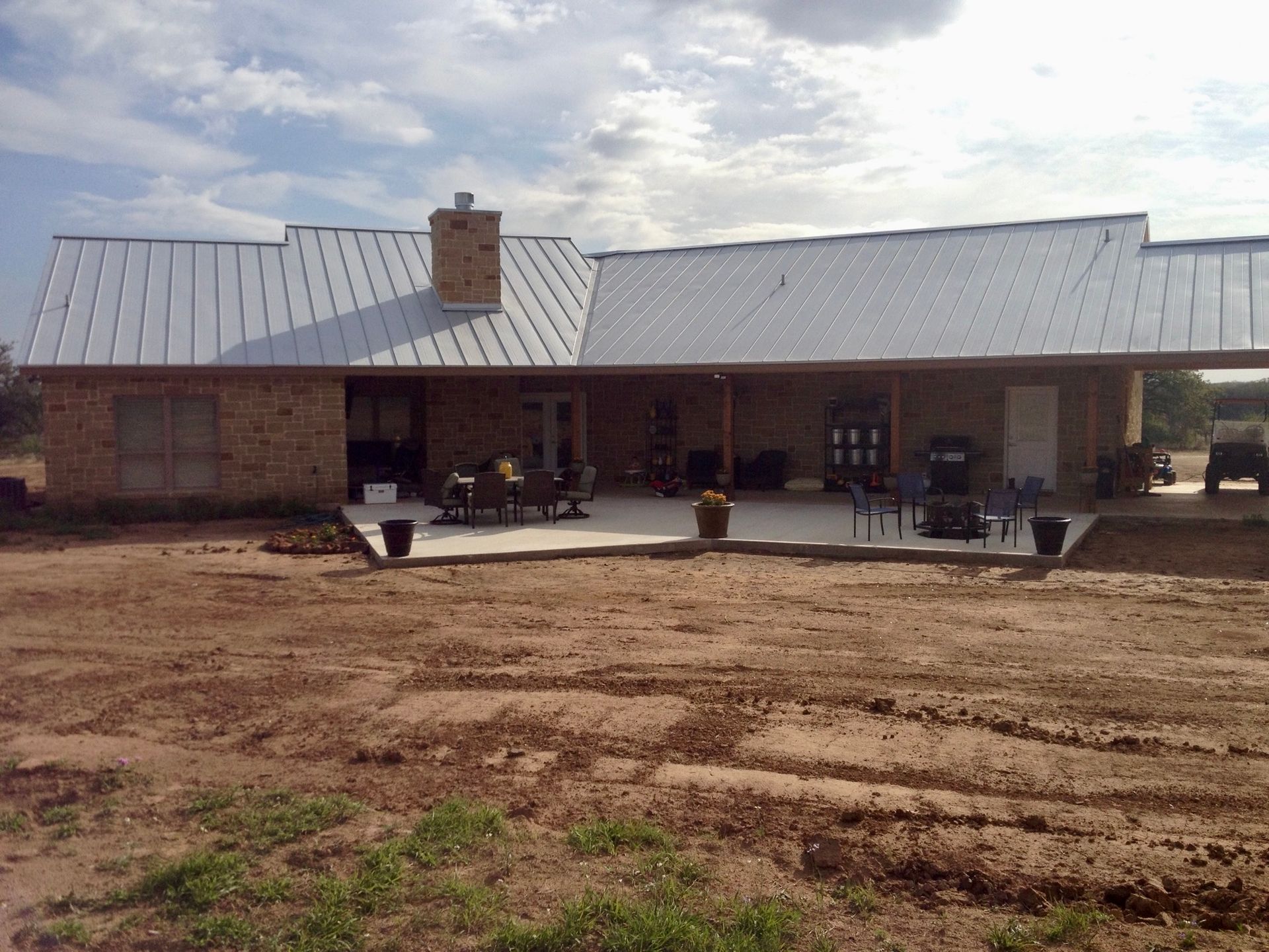 Stone home with metal roof and large back porch with carport