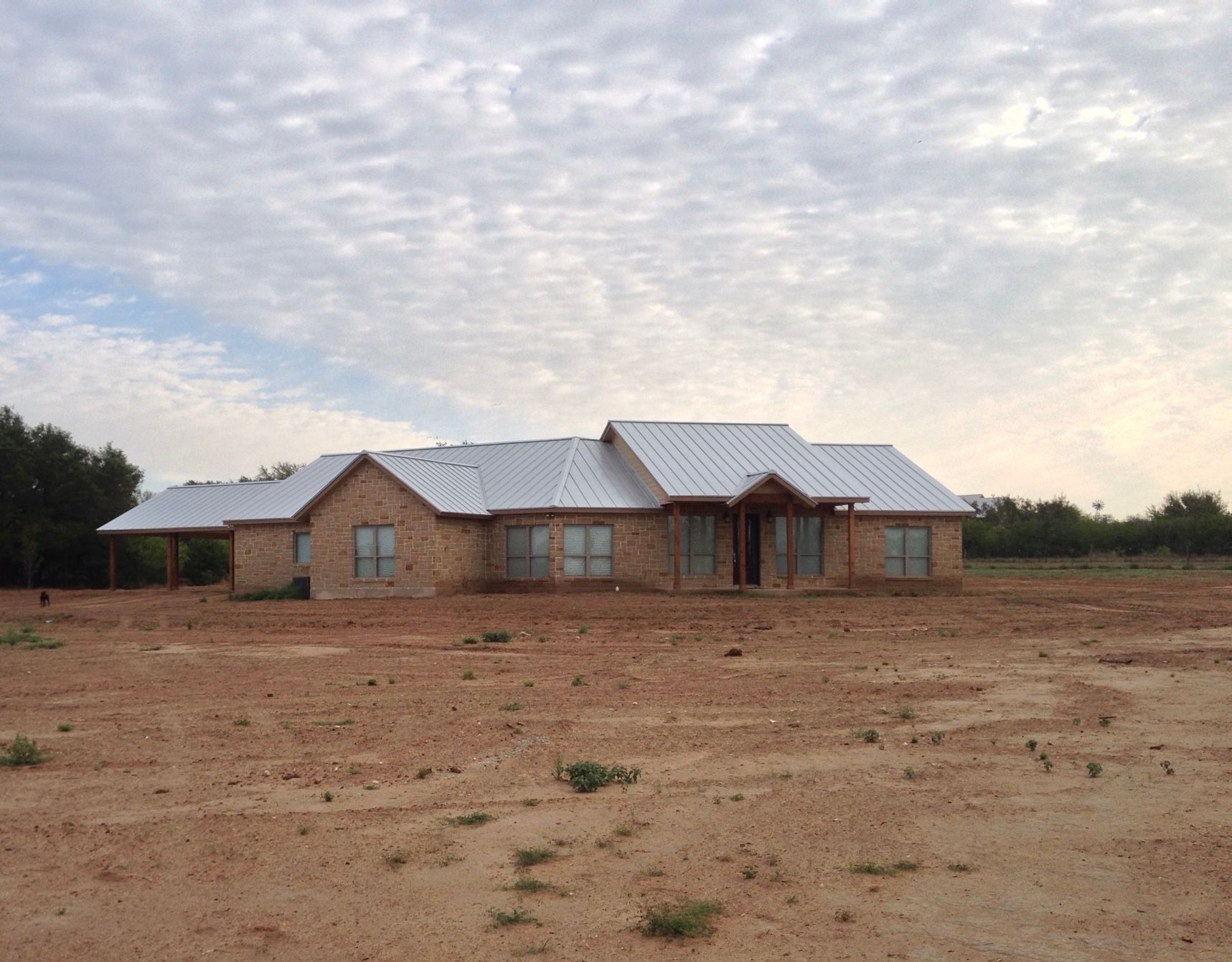 All stone home exterior with metal roof and front porch