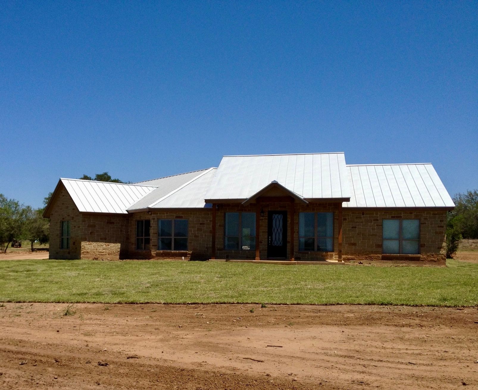 Front view of complete stone home with metal roof and front porch entrance