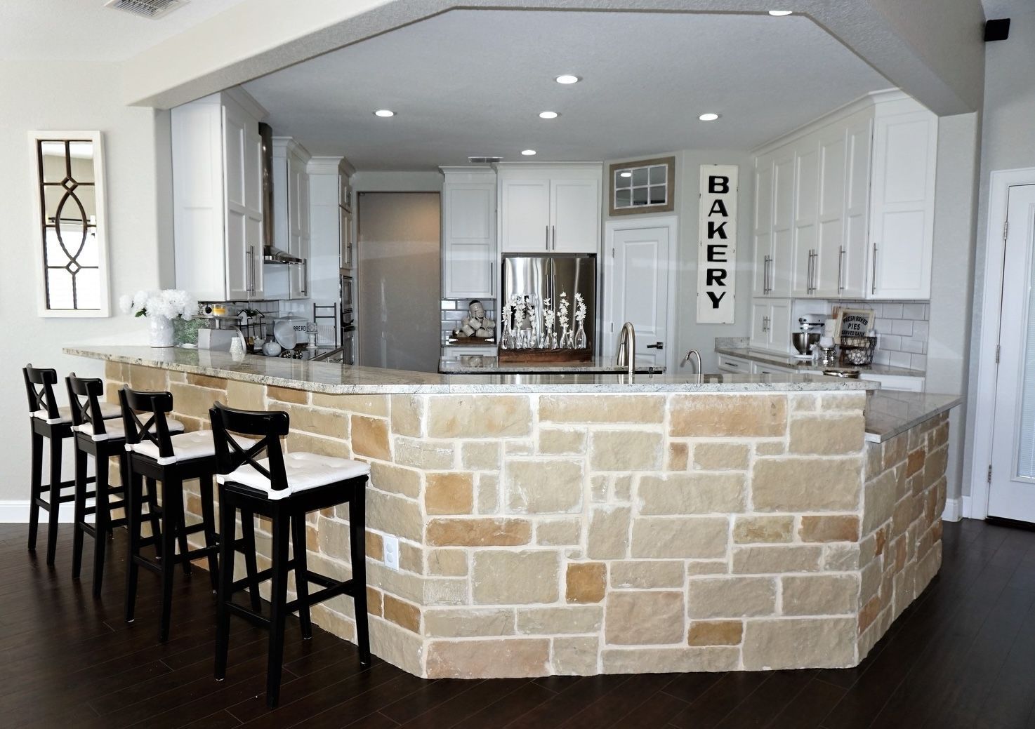 White kitchen cabinets with stone feature pony wall and barstools
