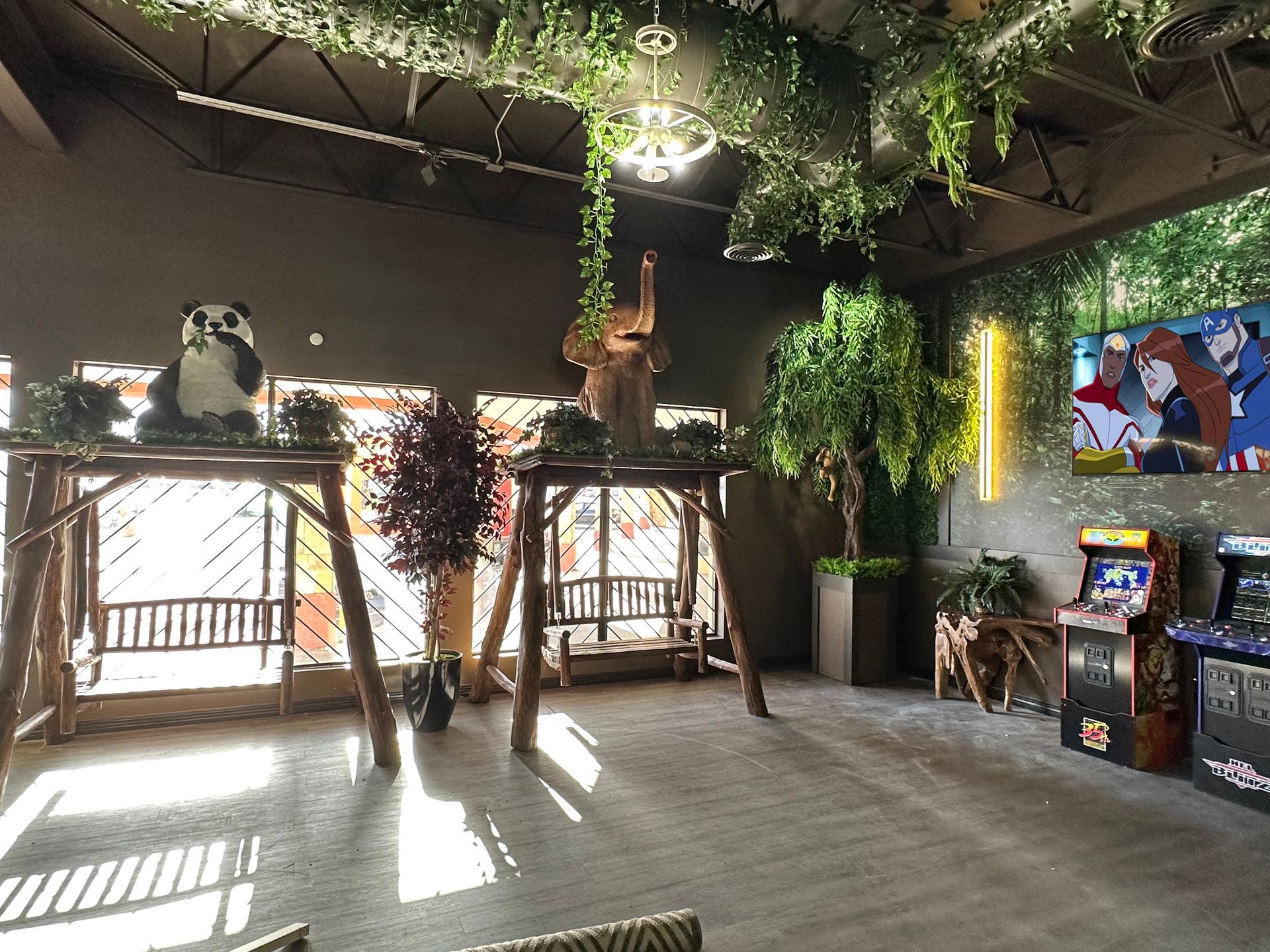 Indoor tropical-themed room with hanging plants, decorative bird statues, and sunlight on the floor