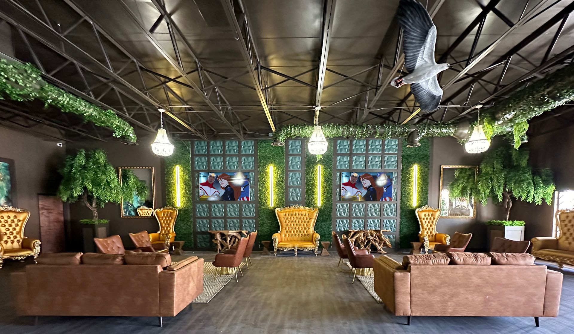 Stylish lounge with tan sofas, yellow chairs, green walls, hanging plants, and geometric ceiling lights.