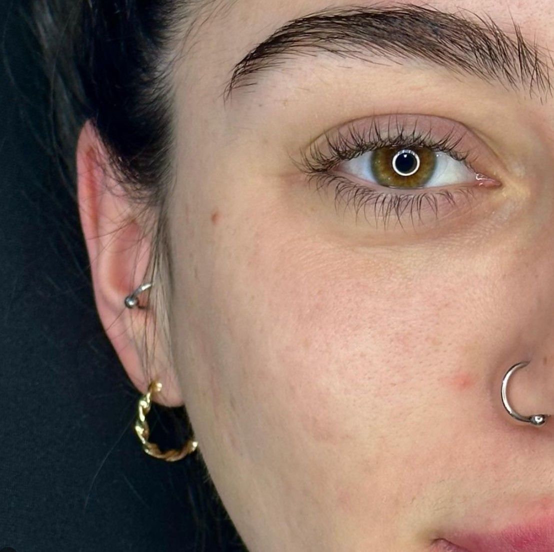 A close up of a woman 's face with earrings and a nose ring.