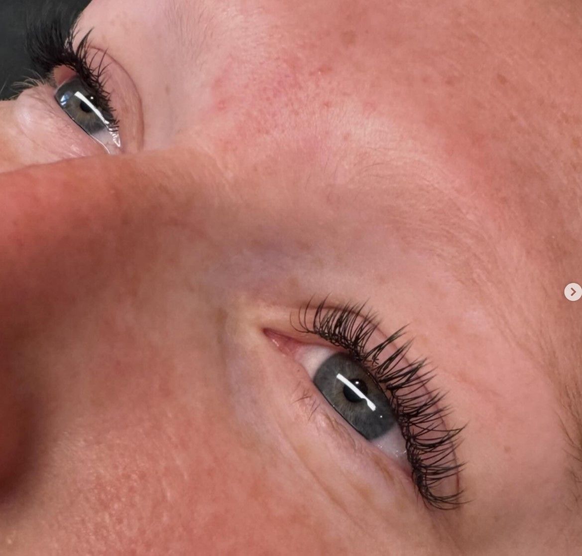 A close up of a woman 's face with long eyelashes and a nose ring.