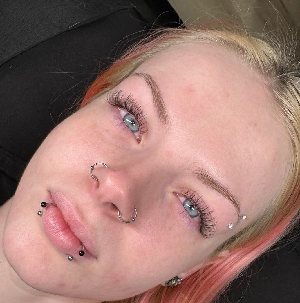 A close up of a woman 's face with piercings and a nose ring.