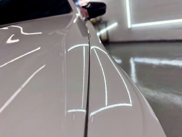 Close-up of a white car door with glossy reflections in a garage or showroom.