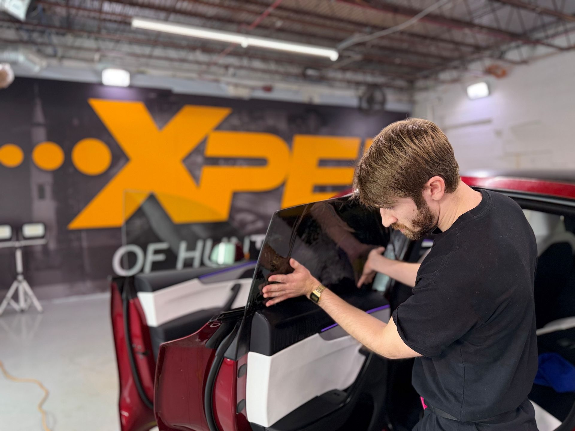 Man inspecting a black and white car in a showroom with an XPeng logo in the background