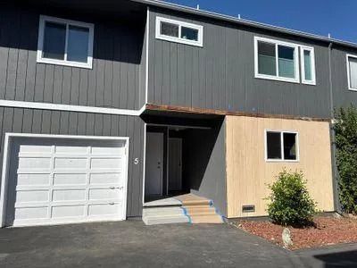 Townhouse exterior with gray and beige siding, white garage door, and windows.