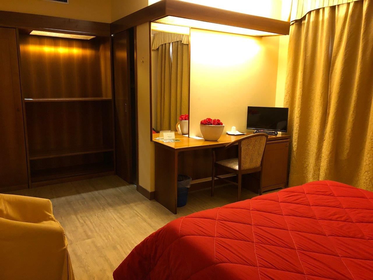 Una stanza d'albergo con un letto rosso e una scrivania