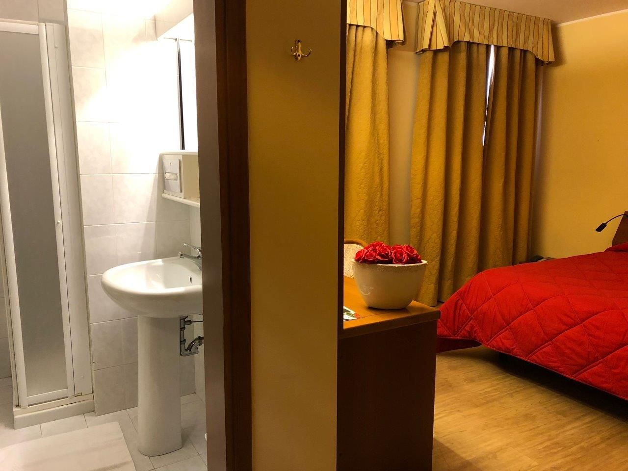 A bedroom with a red bed and a sink
