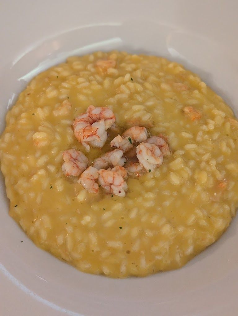 A close up of a bowl of food with shrimp on top.