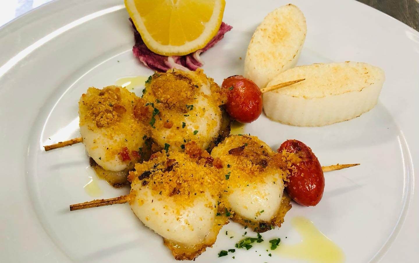 Un piatto bianco con sopra del cibo e una fetta di limone.