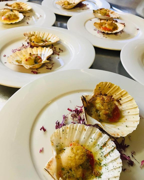 Several plates of food with scallops on them are on a table.