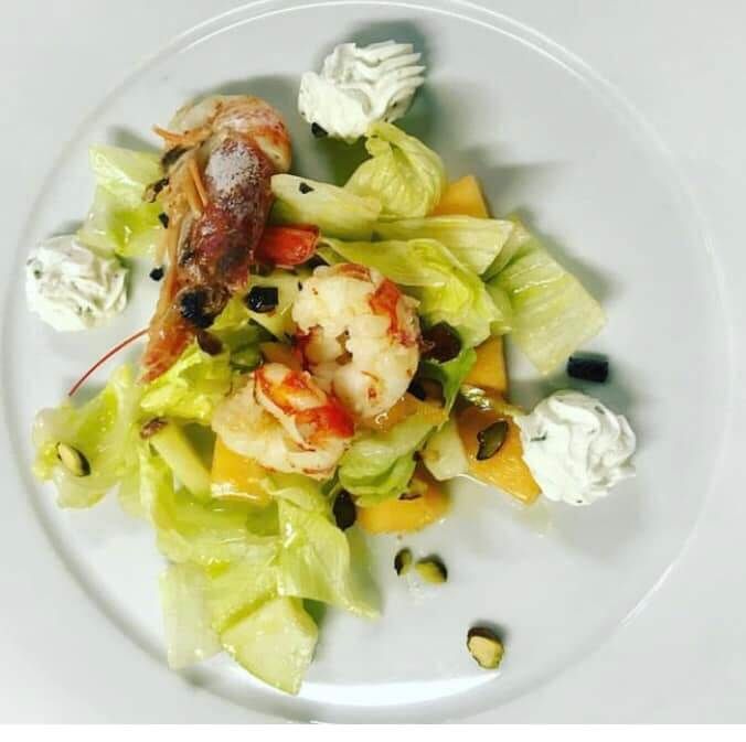 Un piatto di cibo con gamberi e lattuga sopra