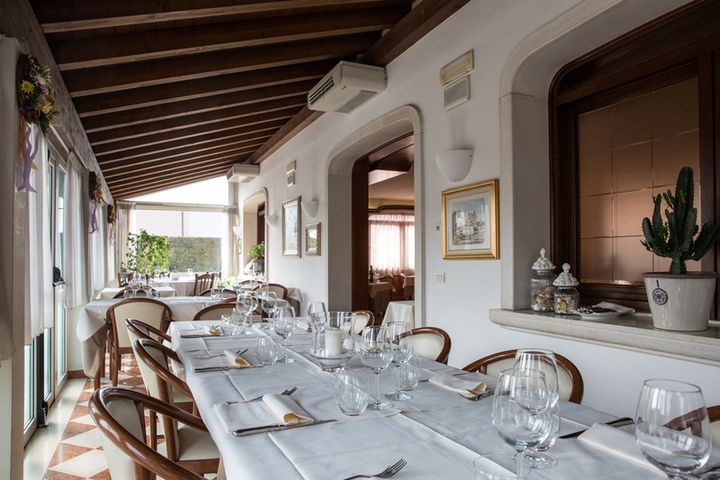 Un lungo tavolo con una tovaglia bianca e bicchieri in un ristorante.