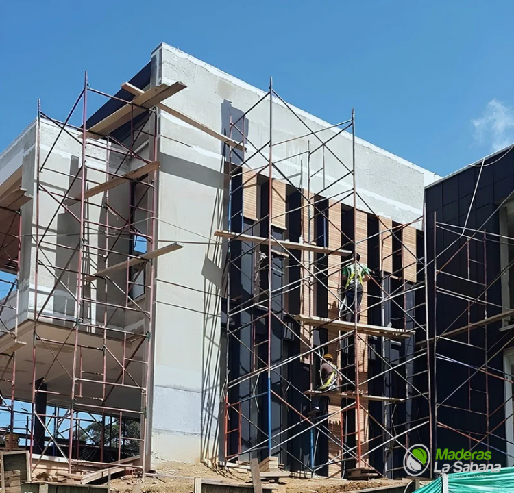Casa moderna en construcción con andamios y paredes exteriores blancas bajo un cielo azul.