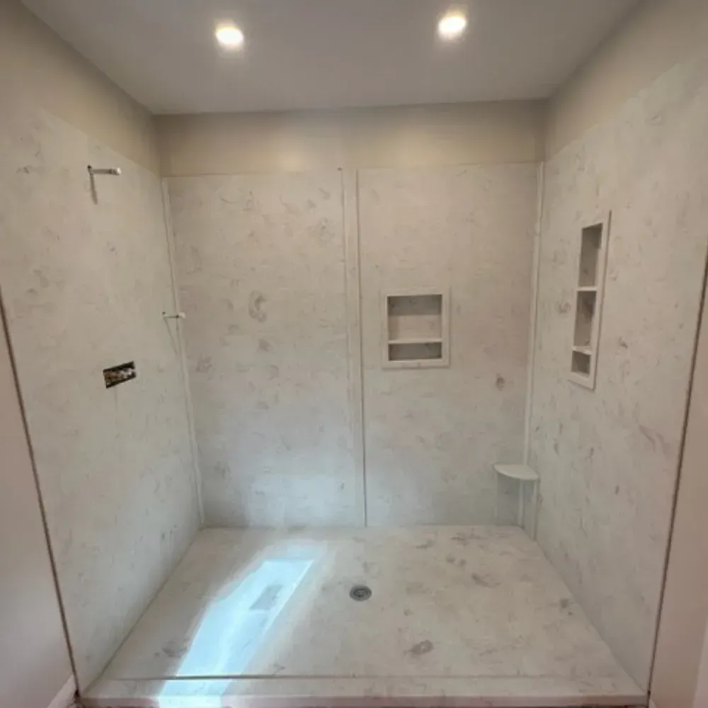 Empty tiled shower stall with recessed wall niches and ceiling lights