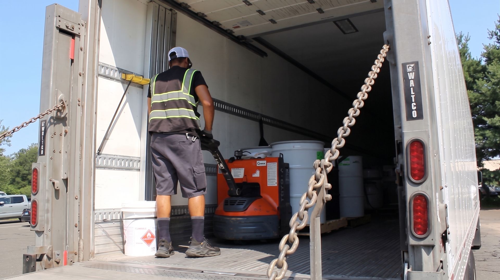 Worker loading equipment into a moving truck from the open back ramp