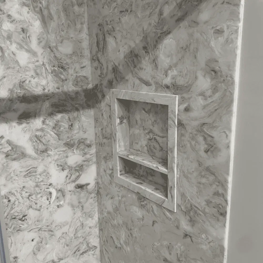 Recessed wall niche with two open shelves, finished in gray marble-patterned tile.