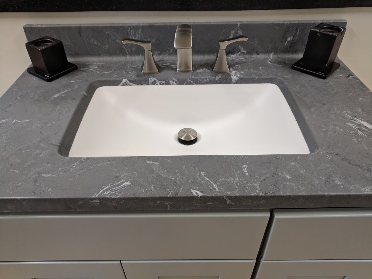 Bathroom sink with gray countertop, white basin, and chrome faucet.
