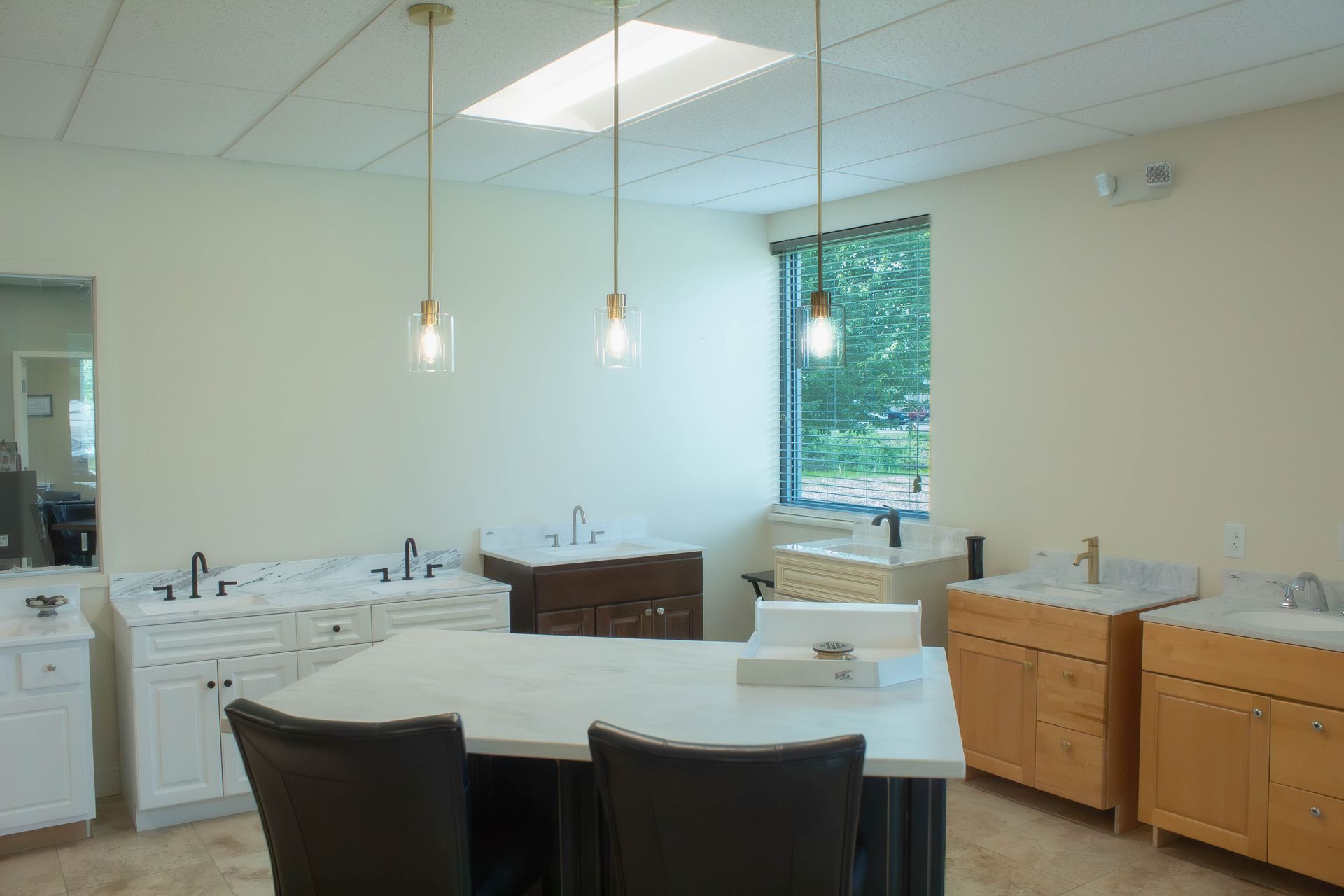 Bright bathroom with white sinks and counters, dark chairs, wood cabinets, and a window with green trees outside