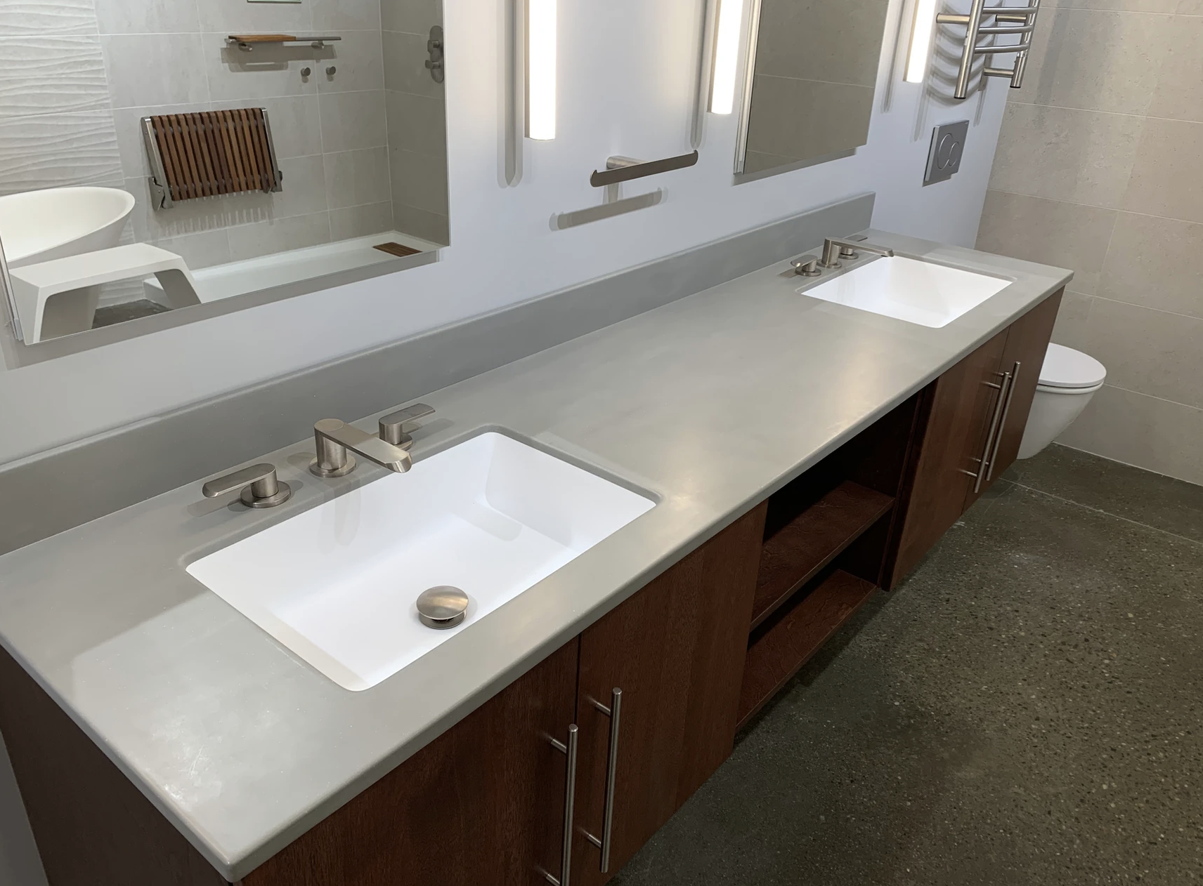 Modern restroom vanity with two white sinks, gray countertop, and large wall mirror