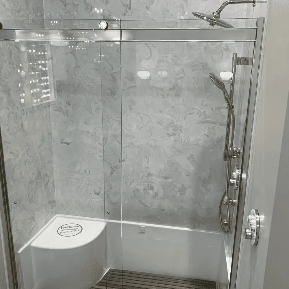 Modern tiled shower stall with glass door, chrome fixtures, and a white corner seat