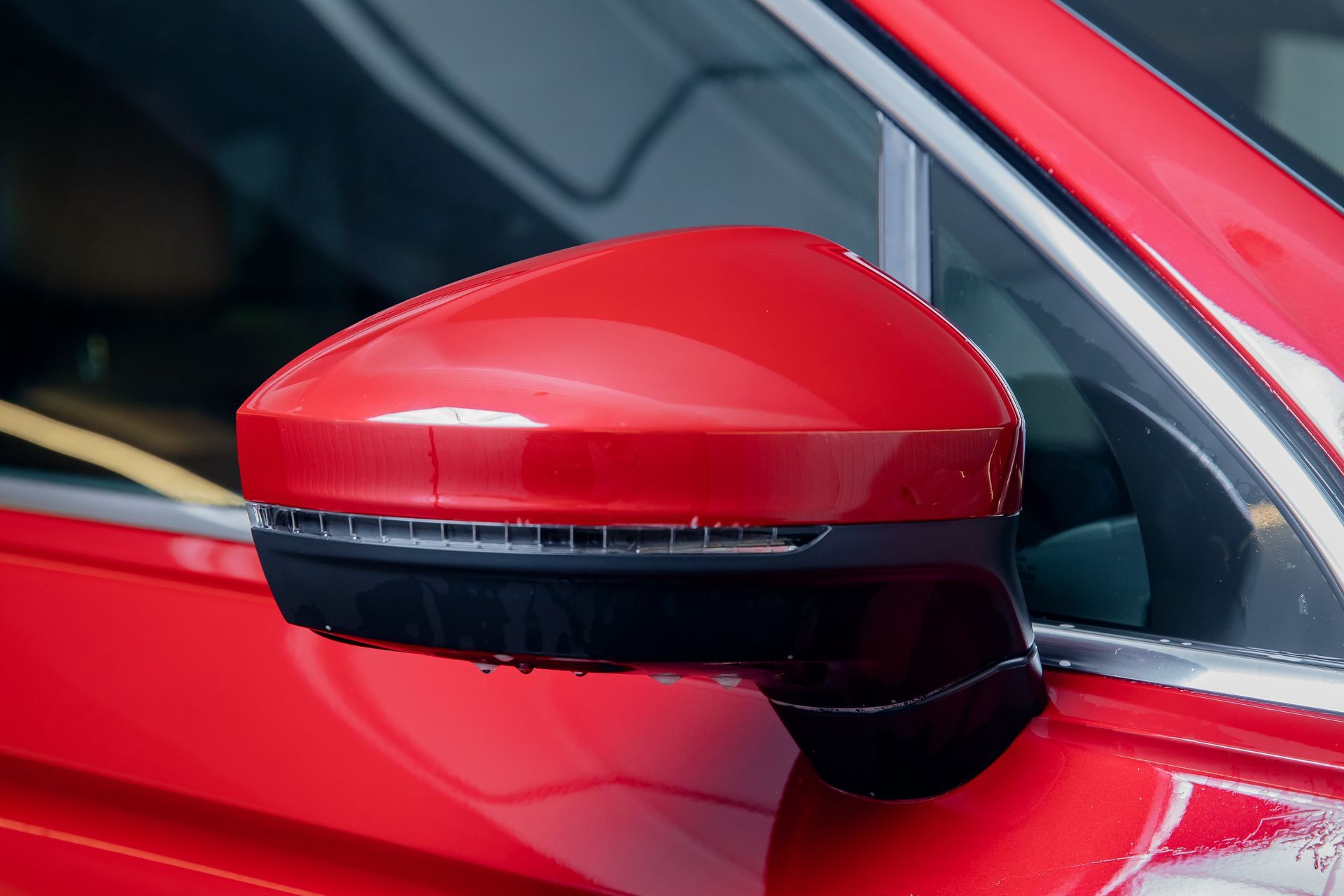 Red car side mirror with integrated turn signal, close-up view