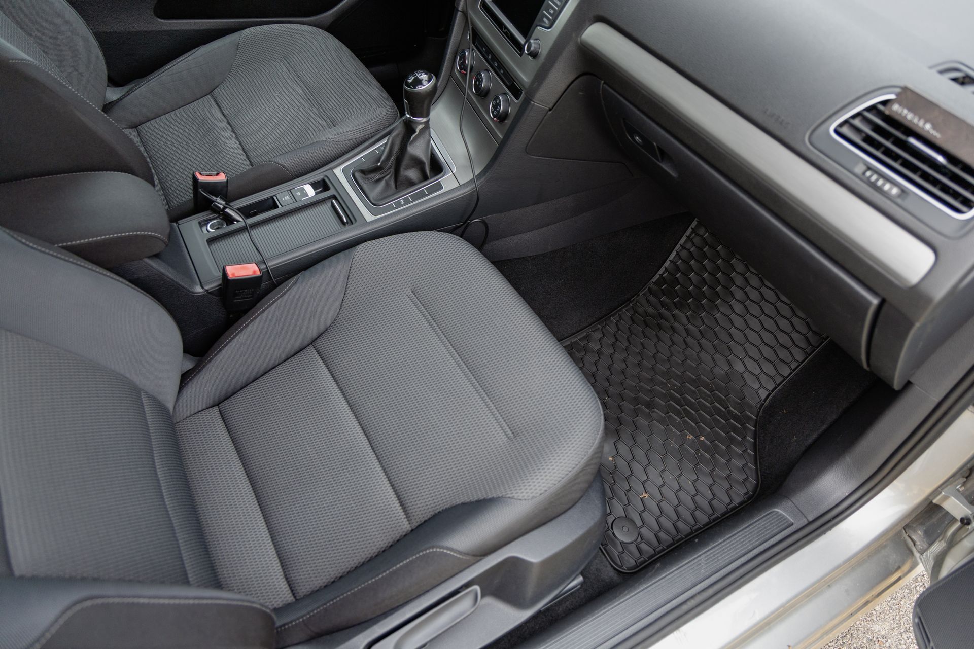 Car interior with dark cloth front seats, center console, and passenger footwell