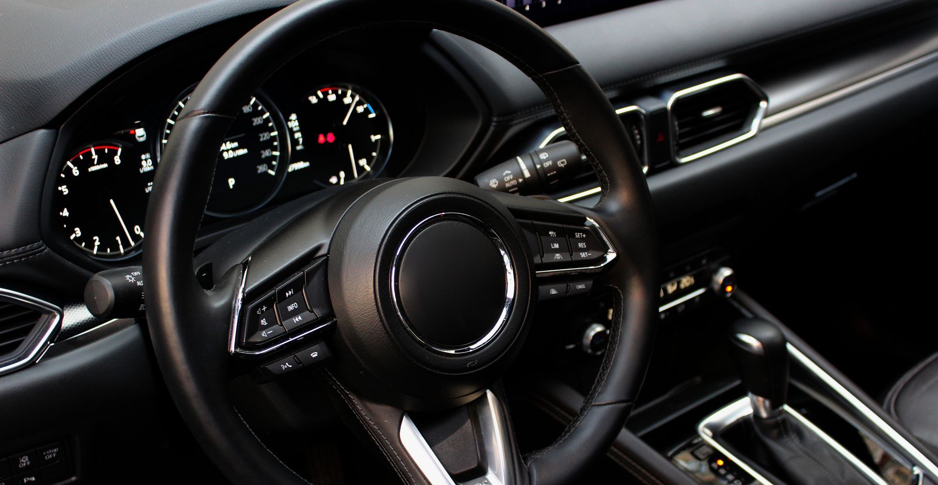 Black car interior with steering wheel, dashboard gauges, and center console visible