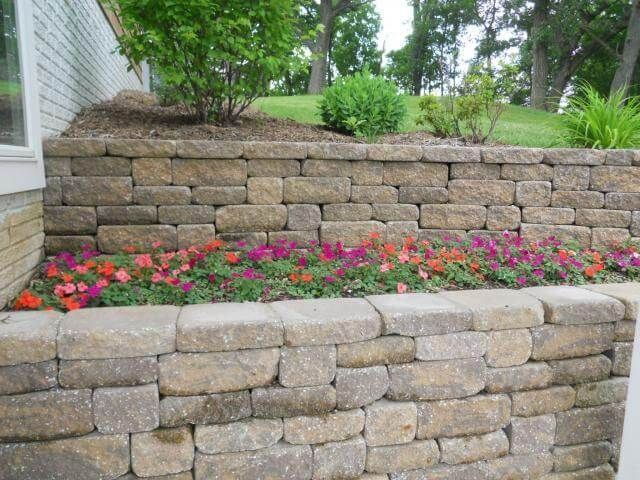 Retaining wall with colorful flowers and green plants.