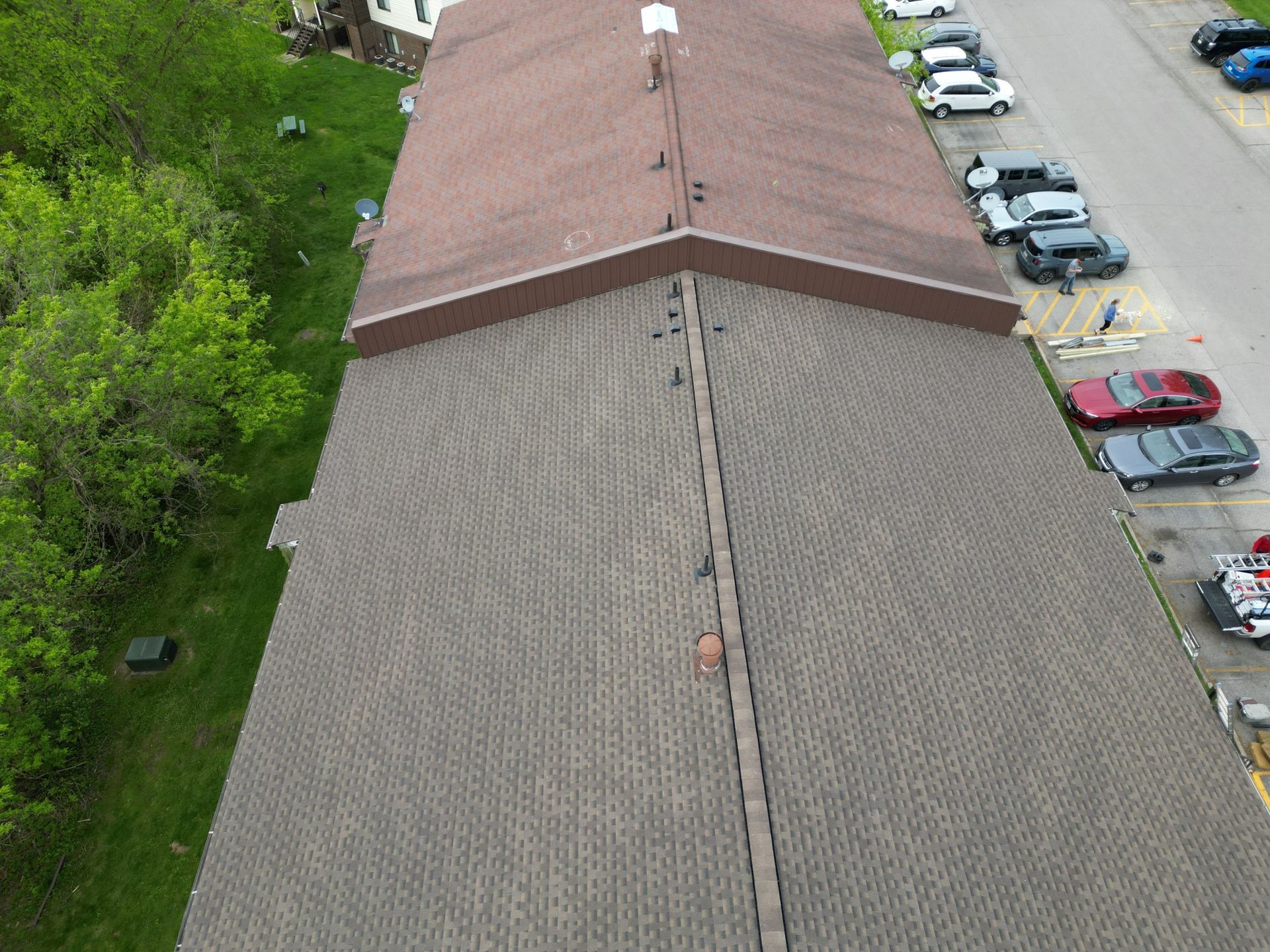 An aerial view of a building 's roof with cars parked in front of it.