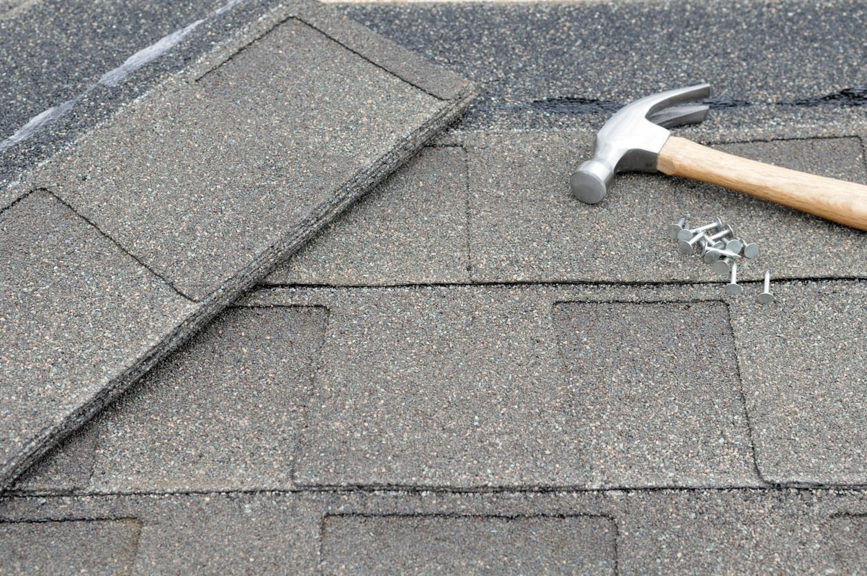 A hammer and nails are sitting on top of a roof.