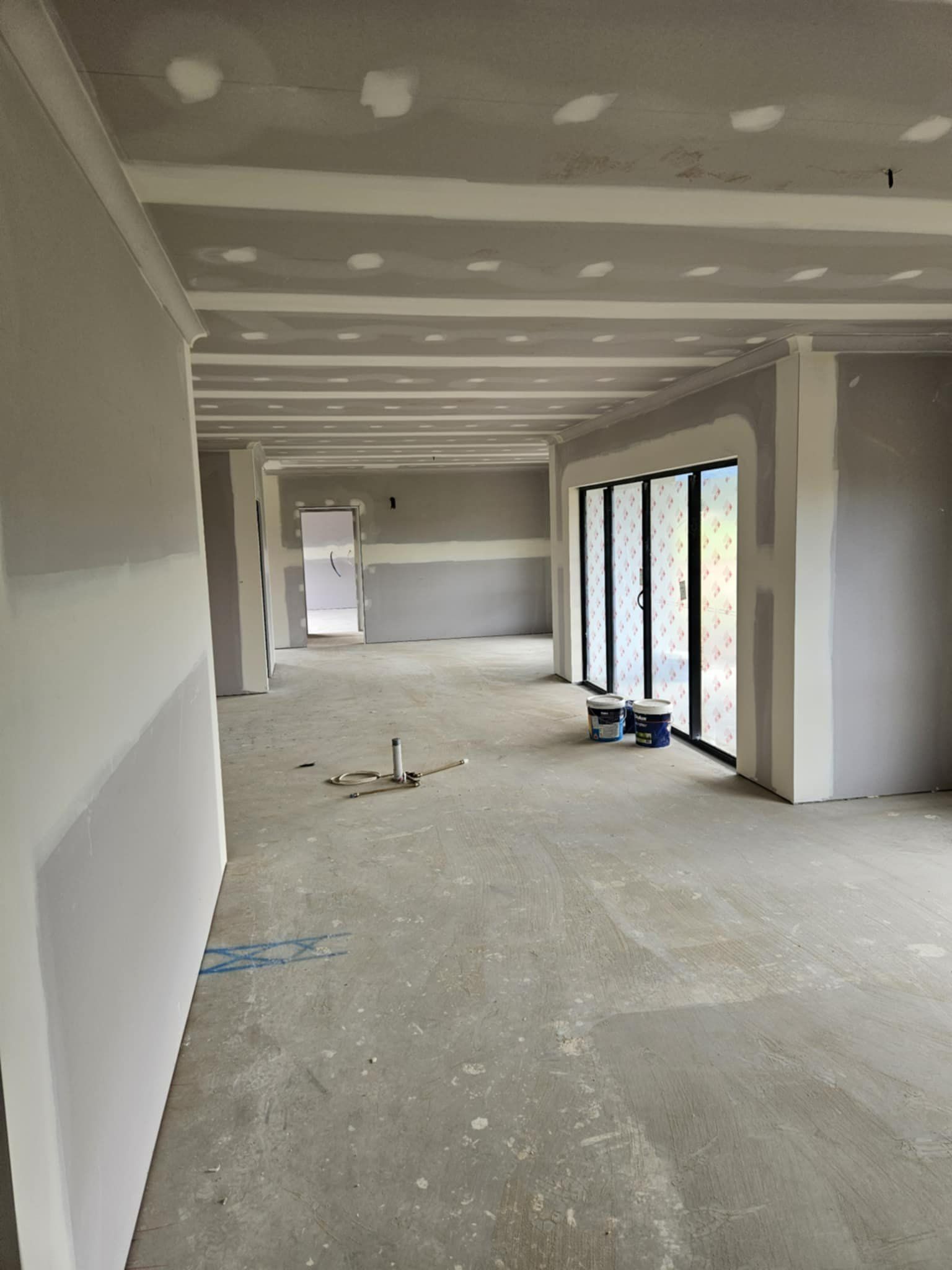 A Large Empty Room With a Plastered Dry Wall — Hams Plastering in Cannonvale, QLD